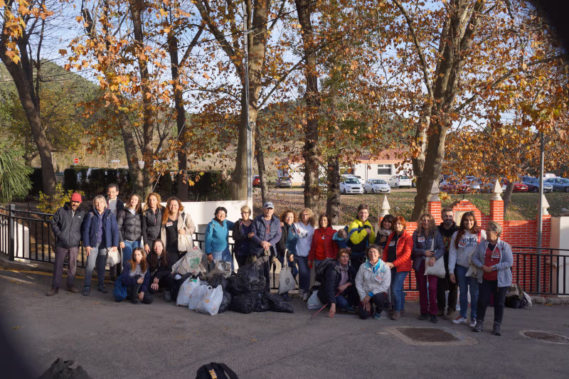 Grupo de personas posando con bolsas llenas de basura recogida del monte