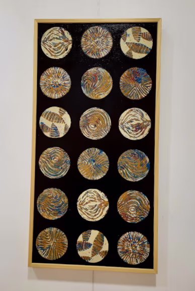 Cuadro en formato vertical en fondo oscuro y 18 formas circulares con diferentes pinturas