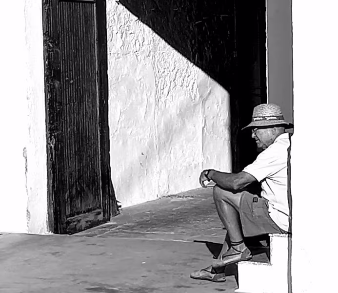Foto de un anciano sentado en unas escaleras