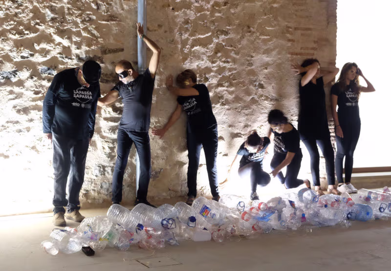 Foto de performance con personas y botellas de plástico